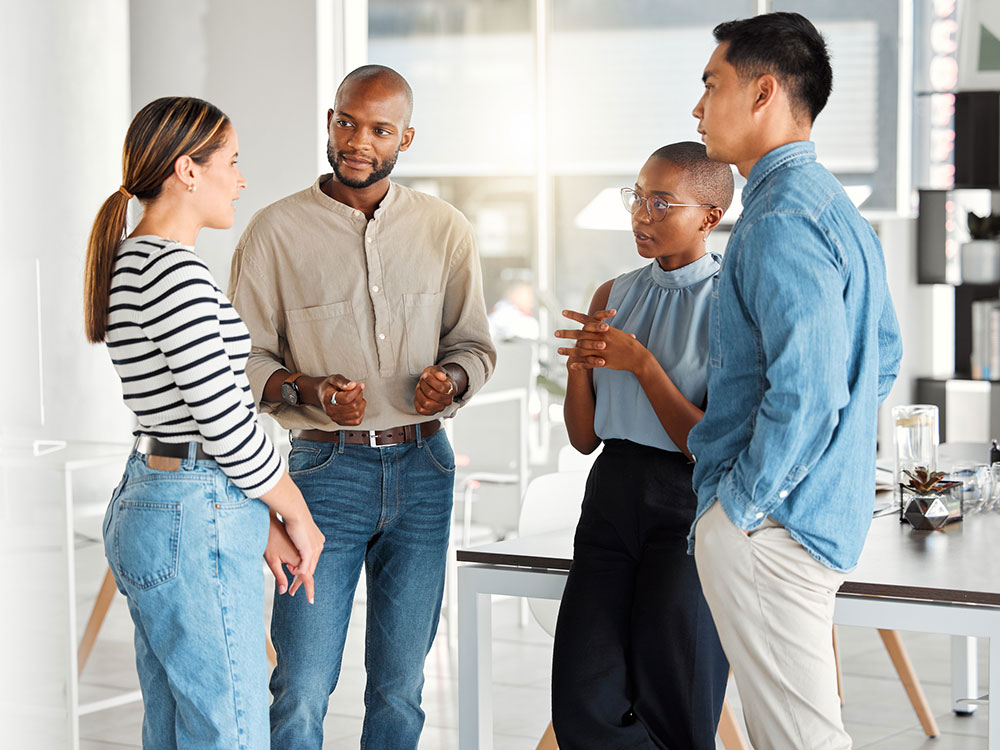 750_careers_-1399563456 Four coworkers standing together and talking during a workplace discussion.