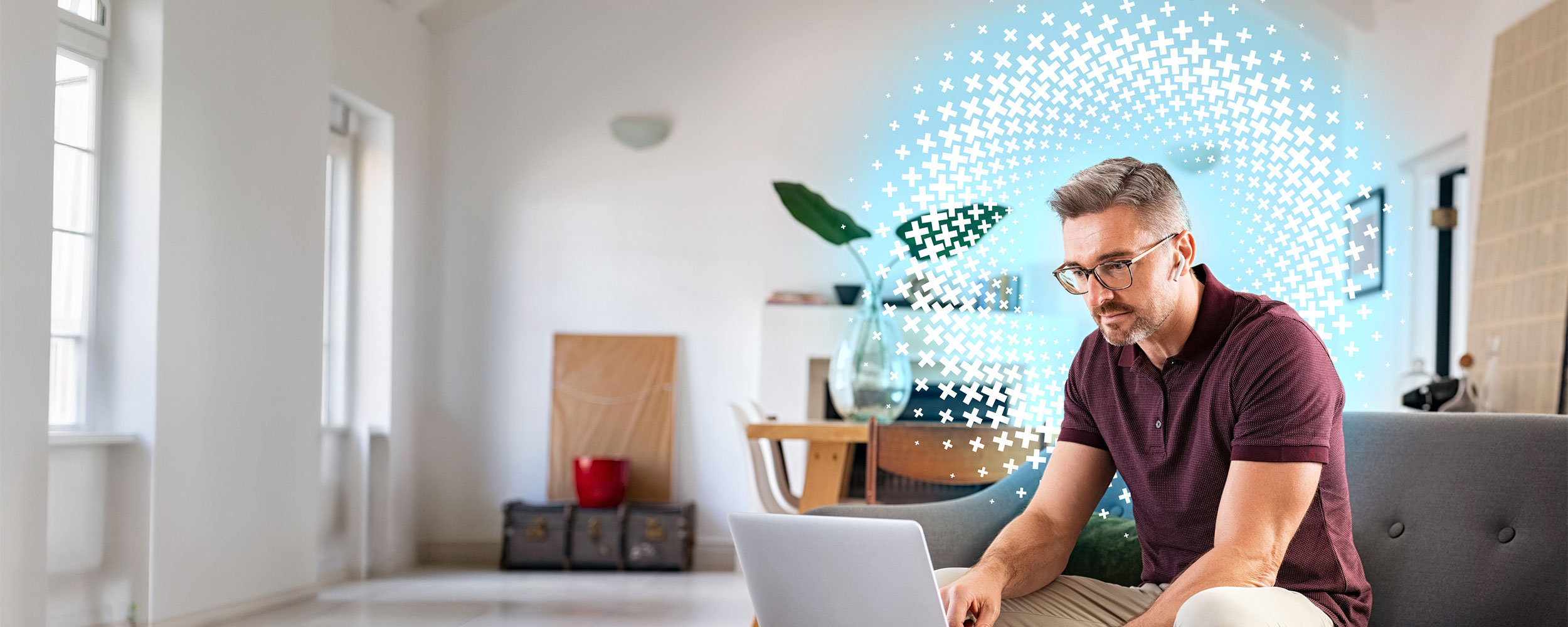 Man using a laptop while seated on a couch at home.