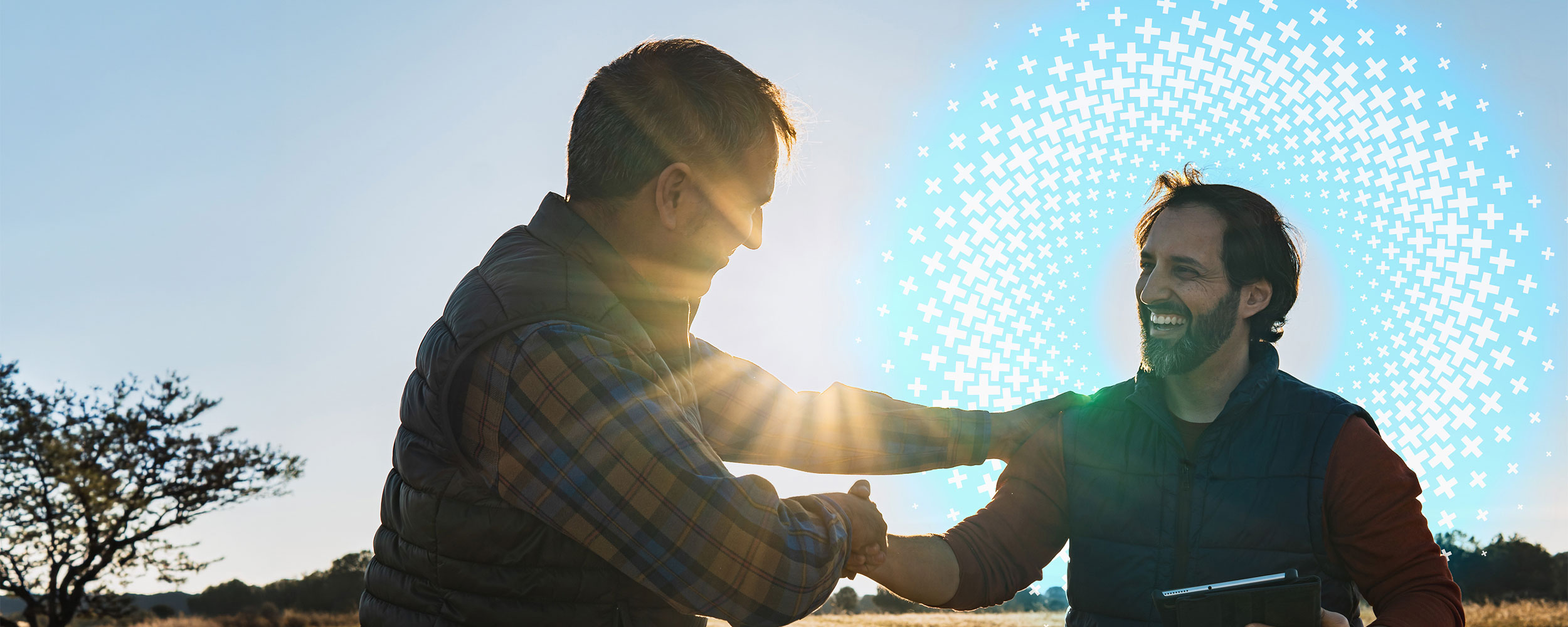 Two men shaking hands outdoors during a friendly business conversation.