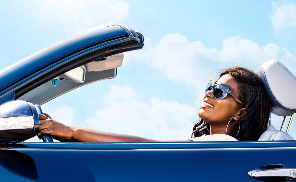 615-auto-loans Woman enjoys driving her new convertible car.