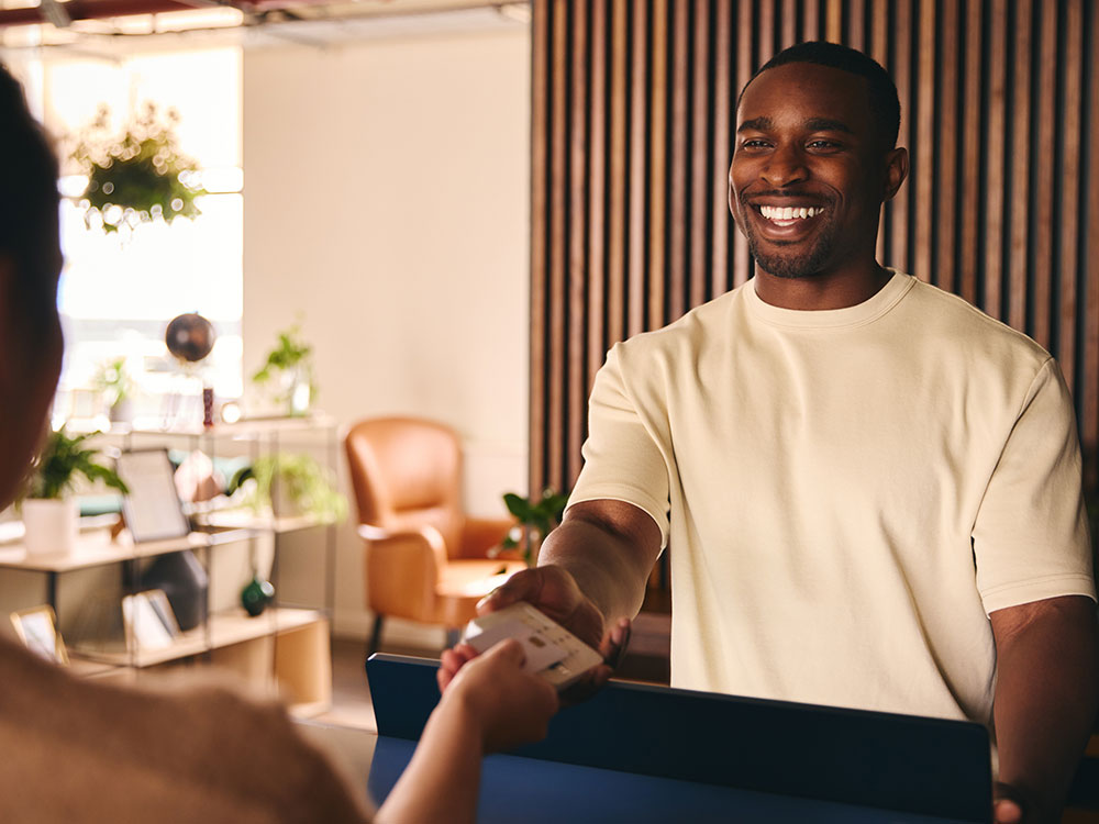 750-1408417712 Smiling customer handing a check or document to a financial service representative.