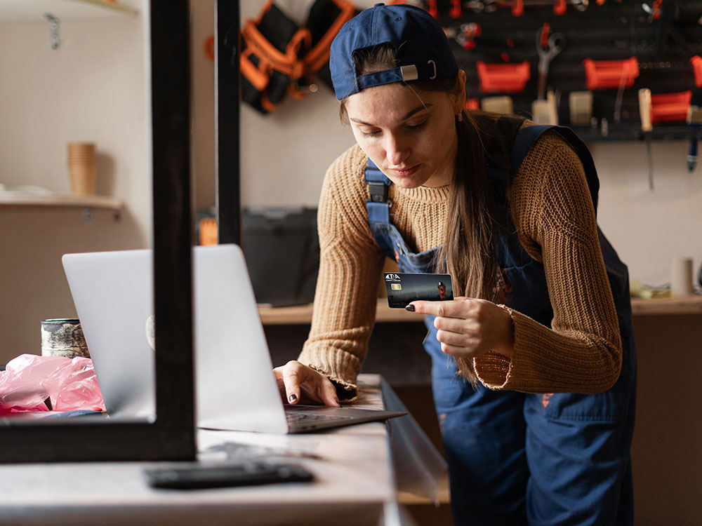 750-2256690263 Woman uses her debit card to buy something online.
