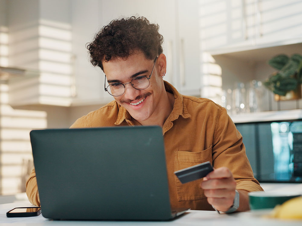 750-getstarted-2227881195 Young adult using a credit or debit card while shopping online on a laptop.