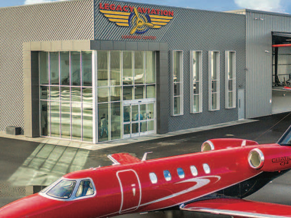 750-legacy-aviation Red private jet parked outside the Legacy Aviation Learning Center hangar.