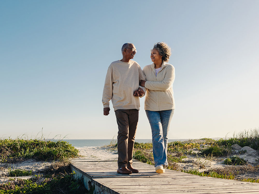 Two seniors take a walk on the beach.