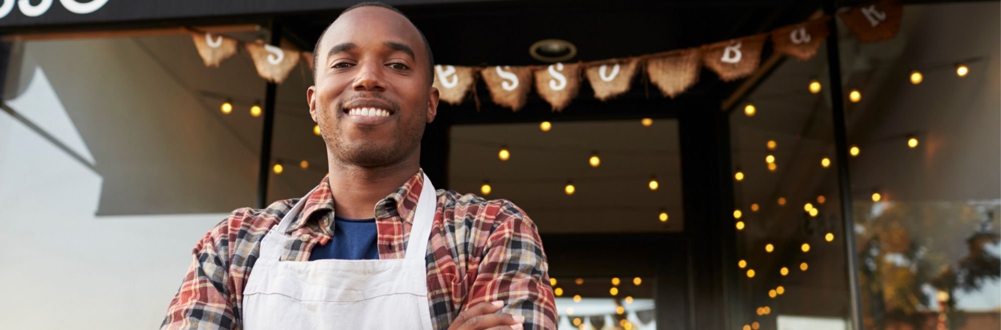 Smiling man standing outside his espresso bar business.