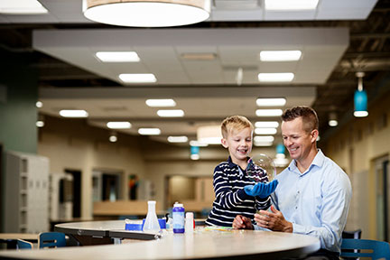 Man helping a young boy play with bubbles in a school