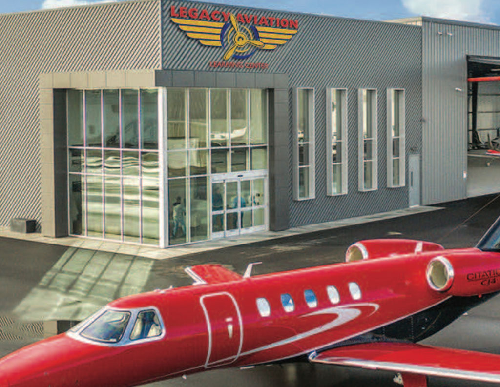 Red jet parked outside of Legacy Aviation Learning Center